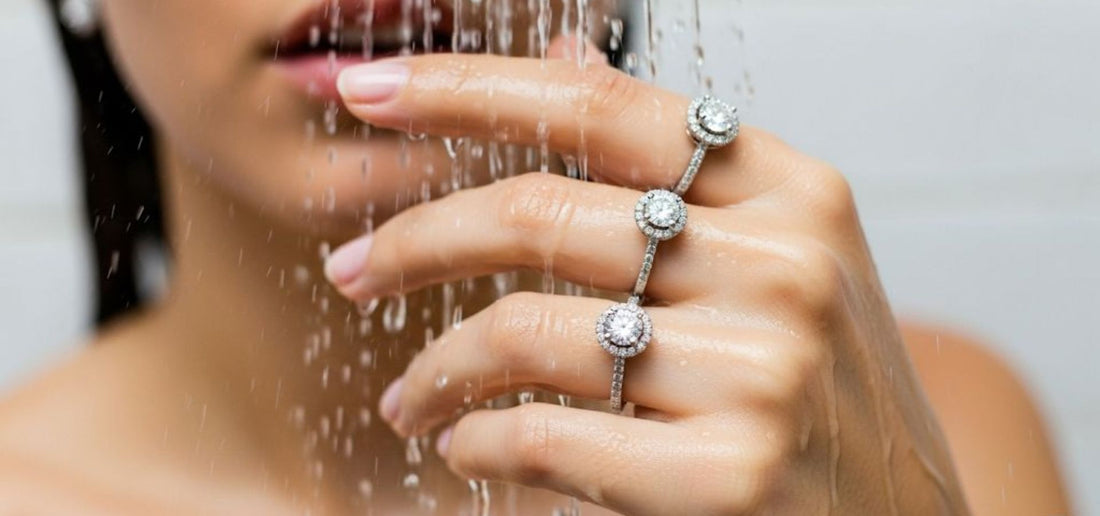A woman's hand adorned with three sparkling round lab-grown diamond rings under running shower water, visually representing Xazina's advice on lab-grown diamond jewellery care.